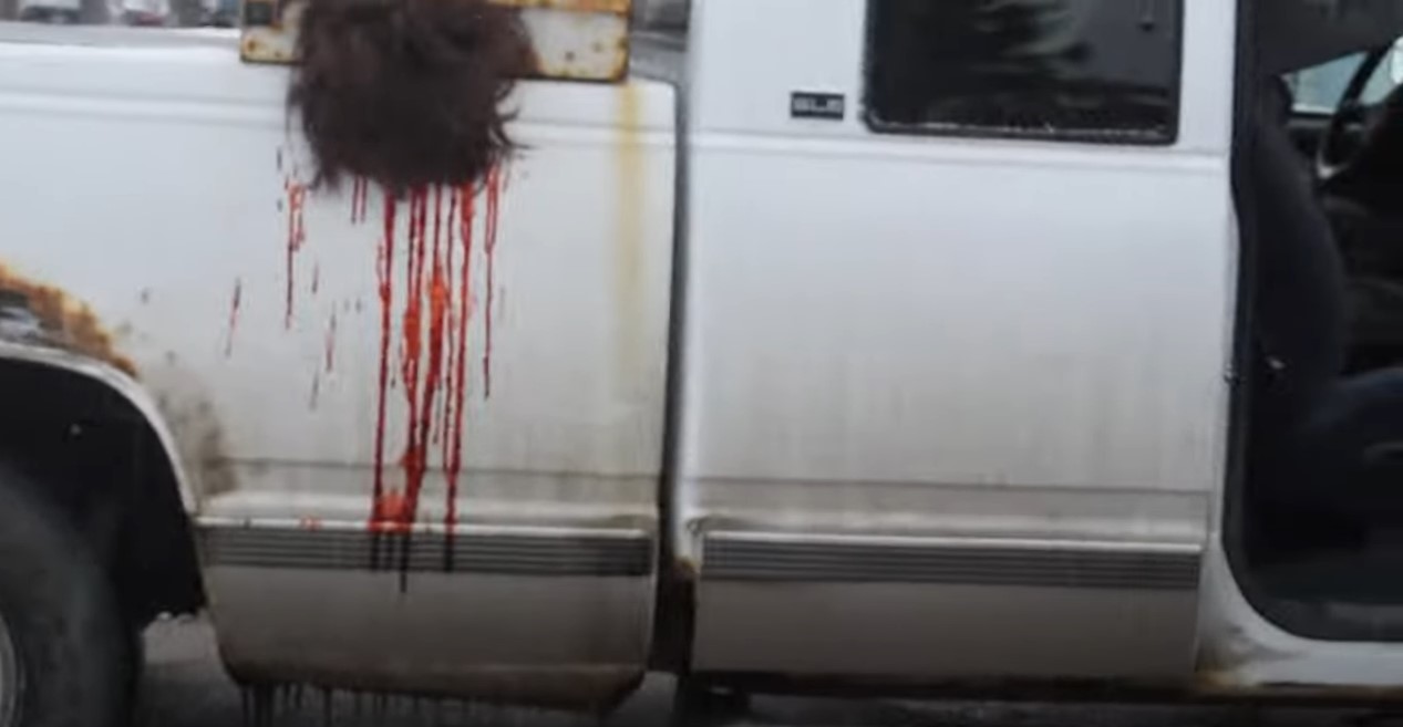 Piture of hair hanging out of back of truck with blood dripping down.